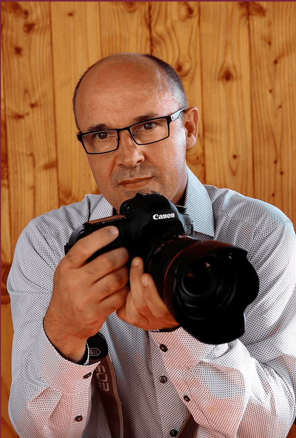 Portrait de Jean Gourlaouen, photographe, tenant son appareil photo